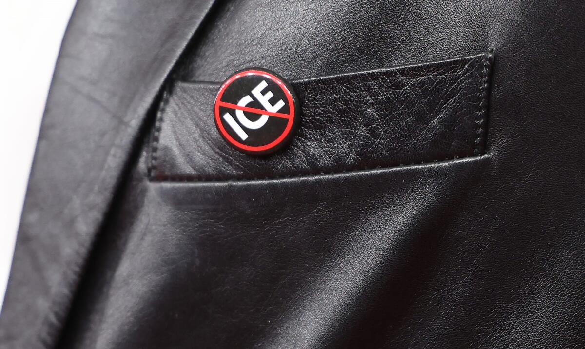 photo of a button with ICE and a red line through it pinned to a leather jacket