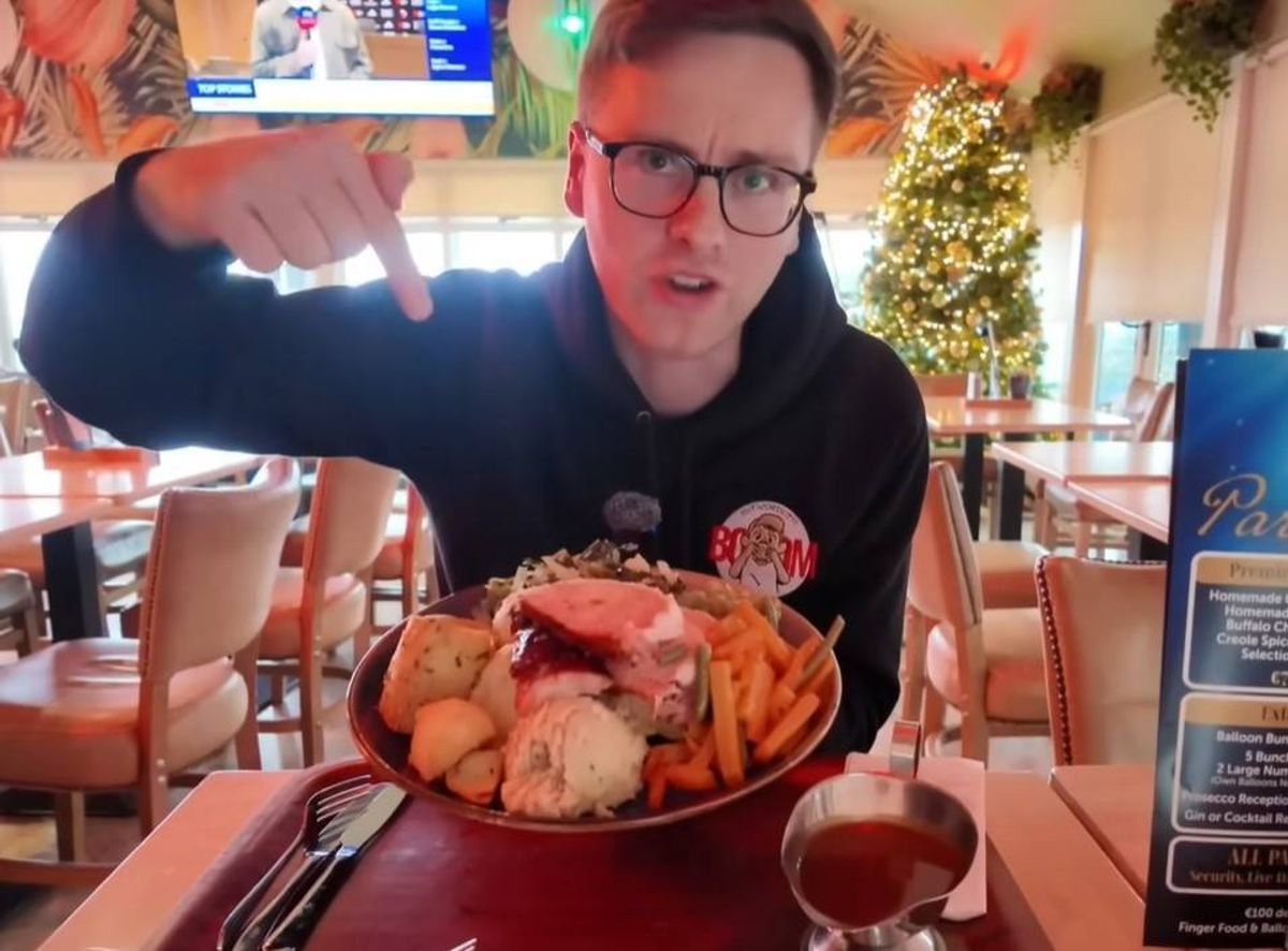 An individual seated at a table in a restaurant, holding a bowl filled with a variety of seafood, likely in the midst of dining.