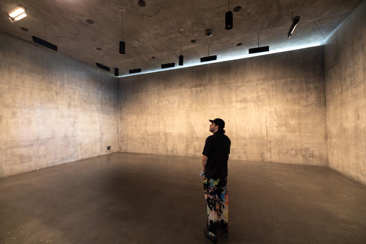 A person stands inside a concrete gallery inside the David Geffen Galleries.