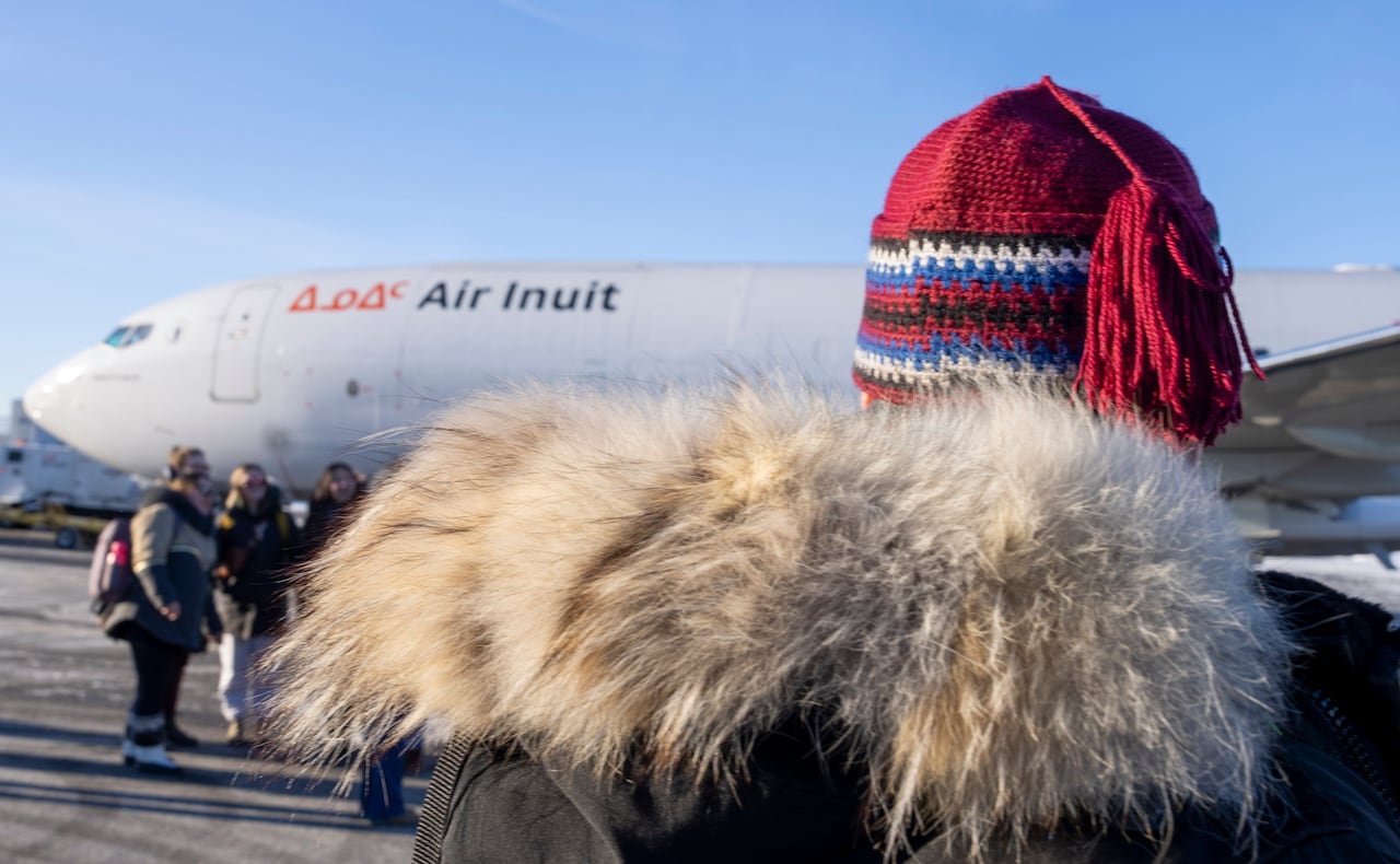 A person is seen from the back approaching an Air Inuit plane.