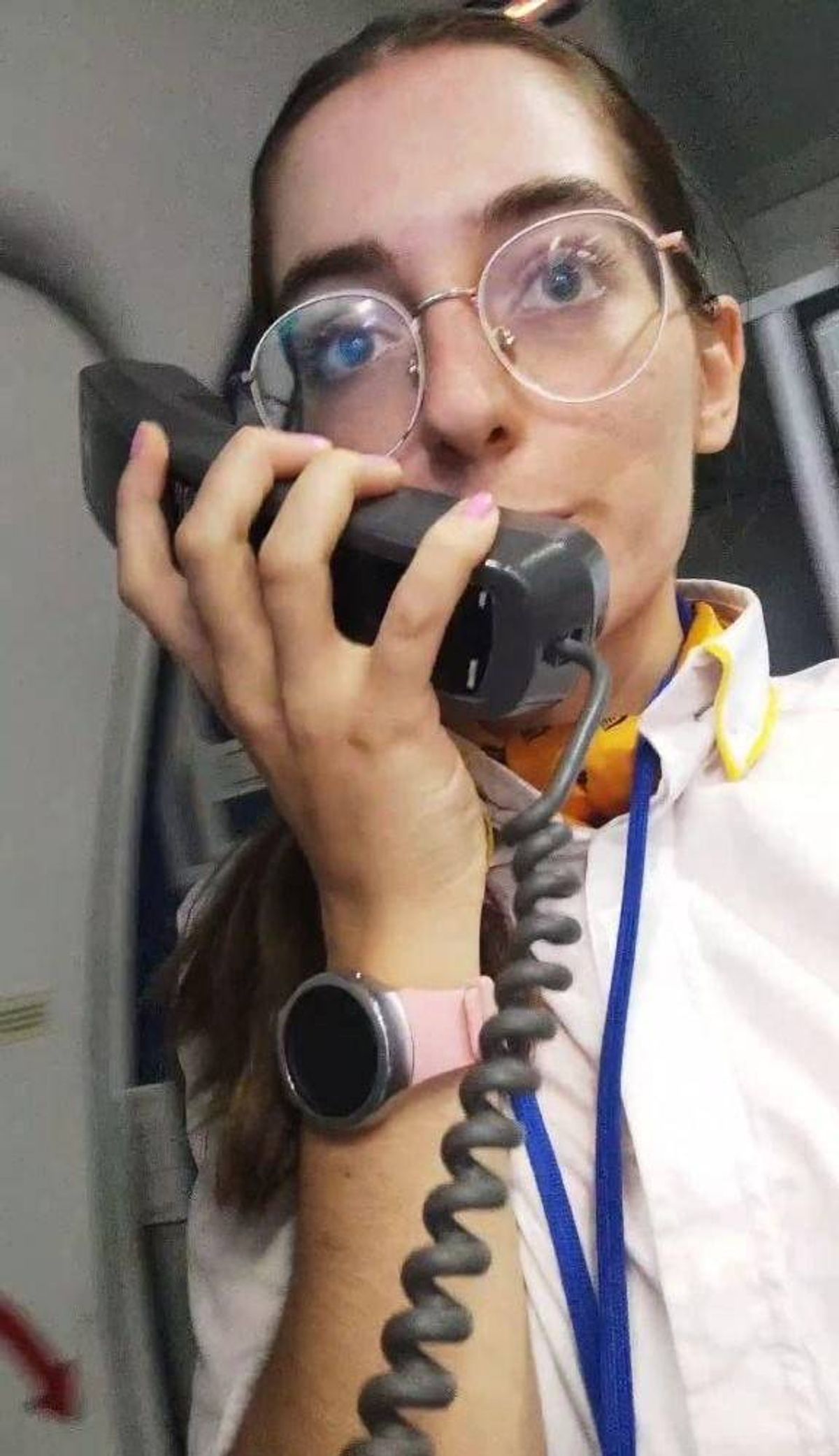 An individual wearing glasses and a white shirt is holding a microphone, possibly engaging in a conversation or recording. The background appears to be an indoor setting with soft lighting.