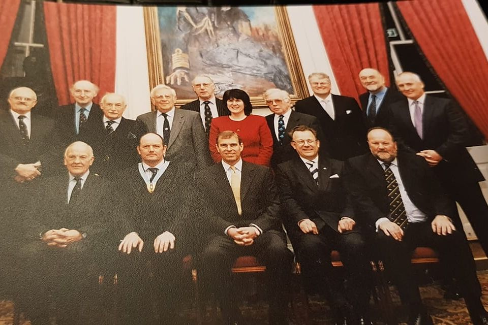 Sheila Bailey standing directly behind Andrew Mountbatten-Windsor.