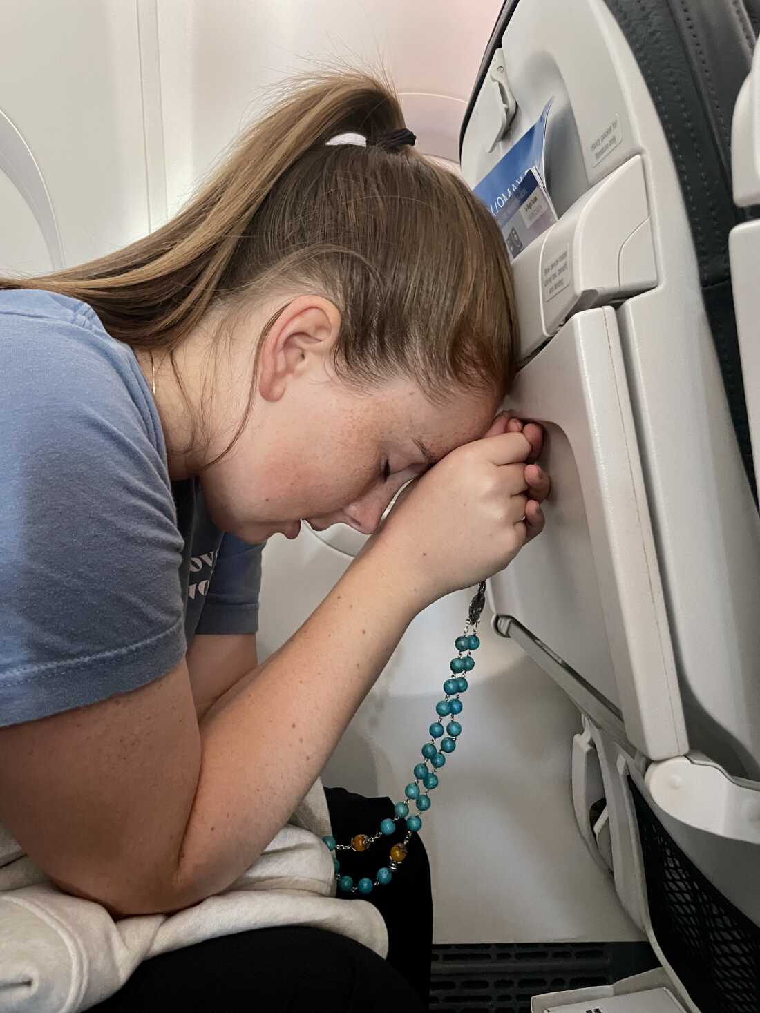 Colette Vance prays with rosary beads on a recent flight to Seattle. Her claustrophobia makes it difficult to travel.