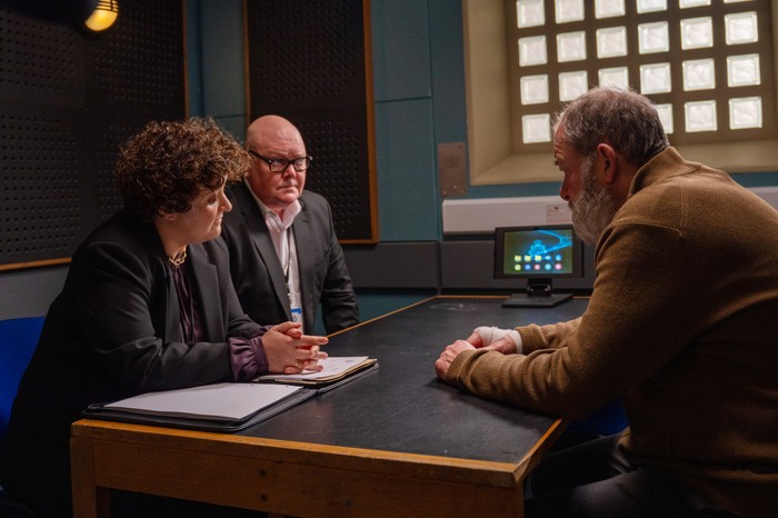 Paddy and a solicitor talk to Bear in a police interview room in Emmerdale
