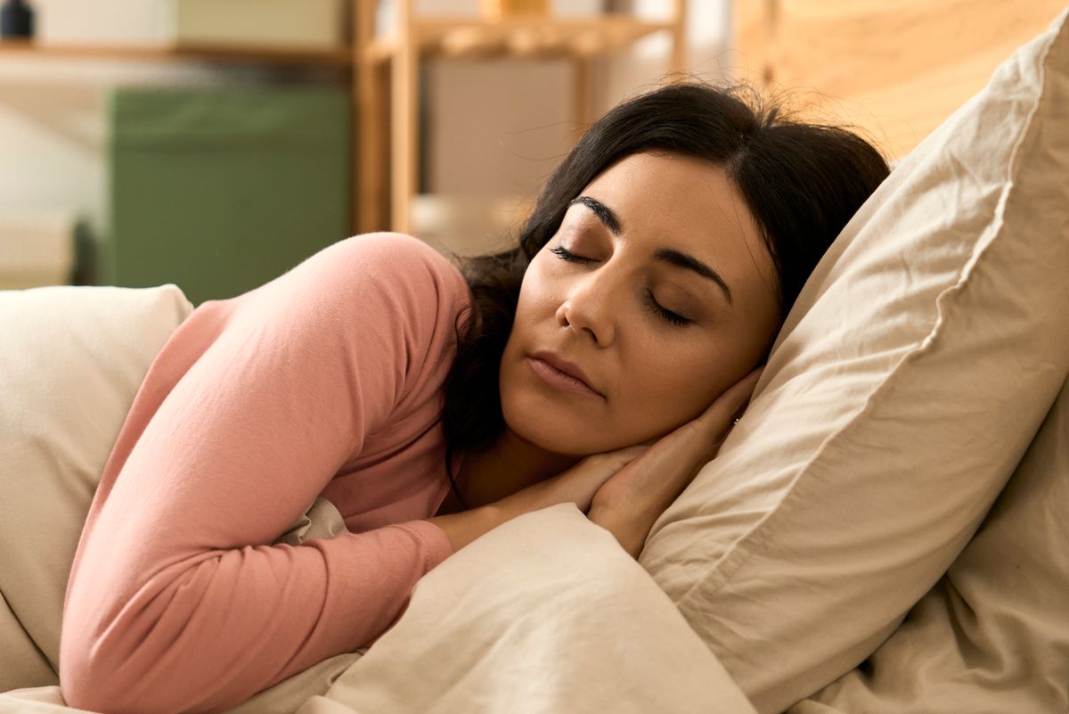 Woman rests peacefully in bed, eyes closed, enjoying comfortable sleep in bedroom