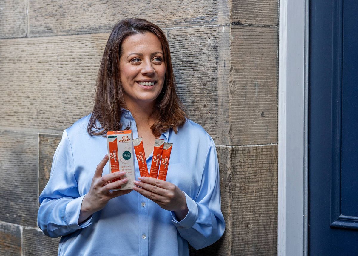 A woman holding the Gut Wealth Liquid Supplement