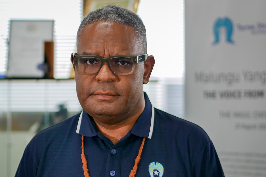 Torres Strait man wearing glasses and dark blue polo shirt.