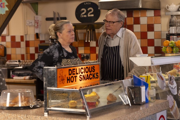Roy and Bernie chat behind the counter of the cafe in Coronation Street