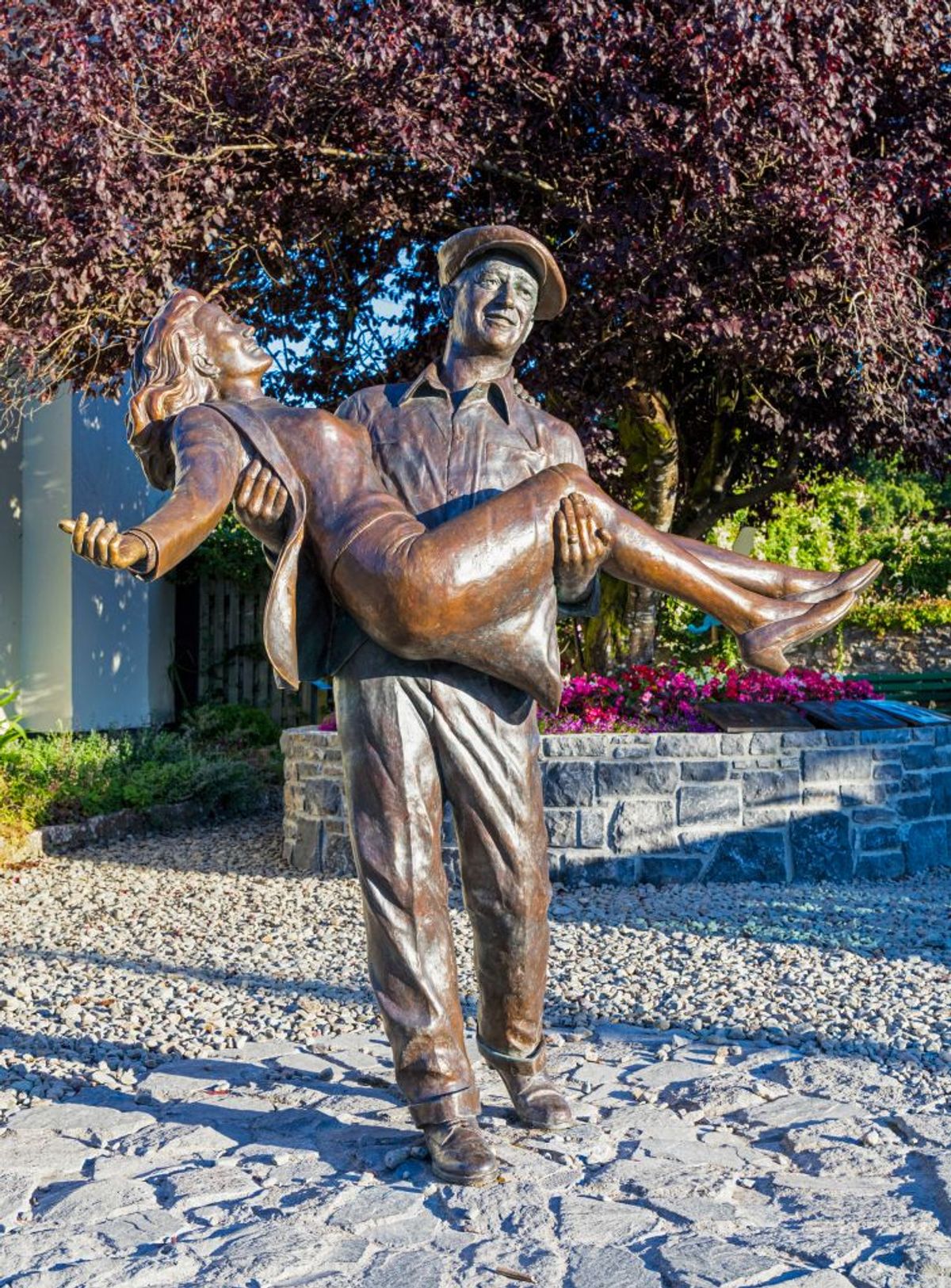 The Quiet Man statue, Cong, County Mayo, Connemara, Republic of Ireland. The statue is based on the theatrical release poster for the film and shows John Wayne as Sean Thornton carrying Maureen OÍHara who played Mary Kate Danaher. The statue is the work of sculptor Mark Rode