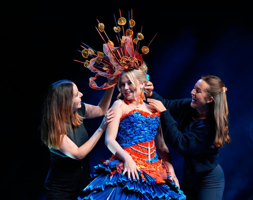 Teachers Sinead Cahill (left) from Tipperary and Gabriela Budaite (right) from Meath make final adjustments to a couture design worn by student Rachel Bruce, Torn by Motor Neurone Disease, made entirely from recycled materials, during the Junk Kouture World Final at the Helix in Dublin. Niall Carson/PA Wire