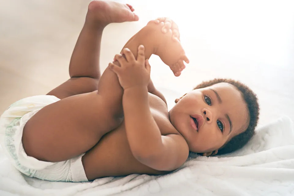 A baby lying on a soft surface, holding its feet, conveying a sense of curiosity and exploration