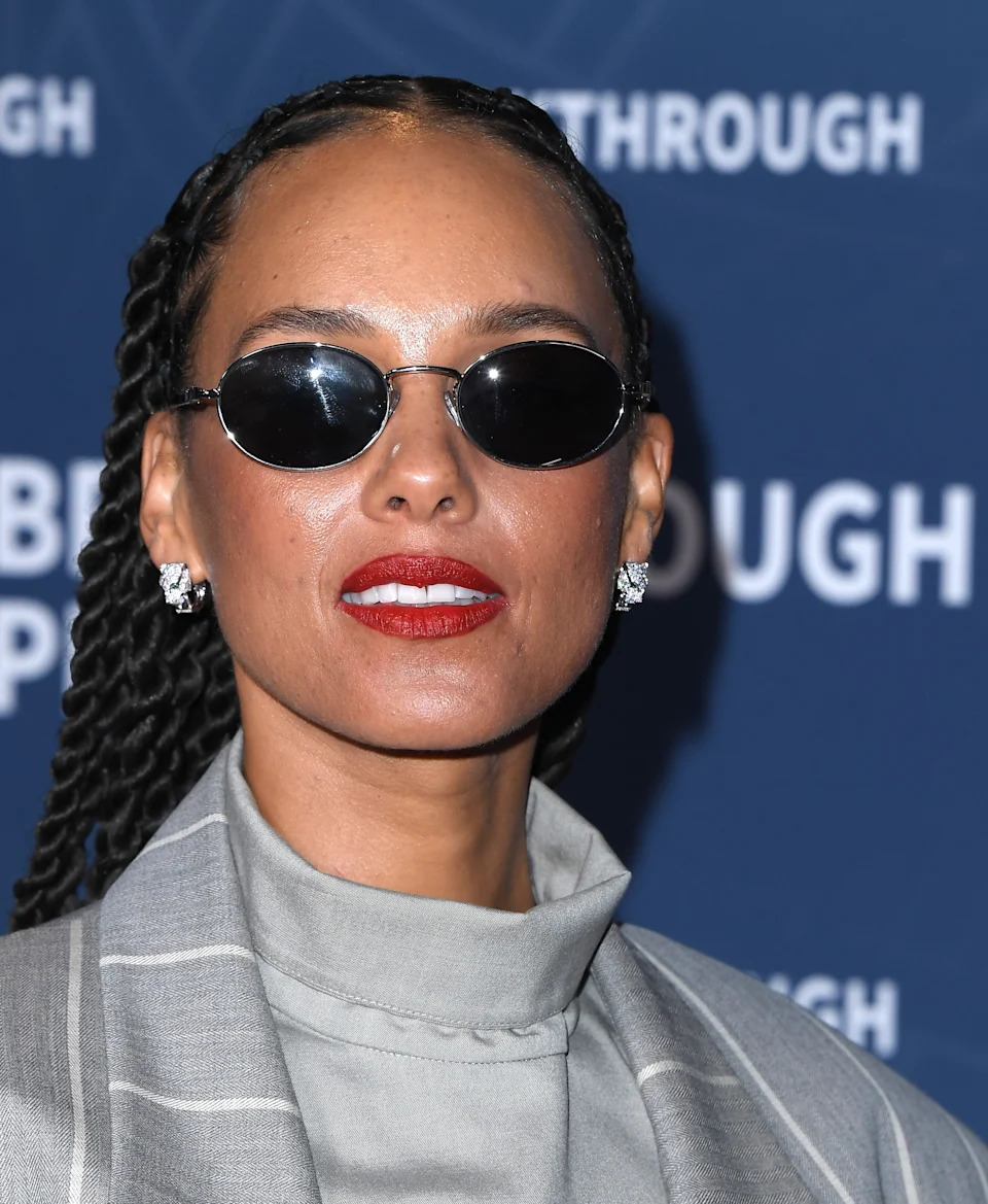 Alicia Keys on the red carpet wearing sunglasses and red lipstick