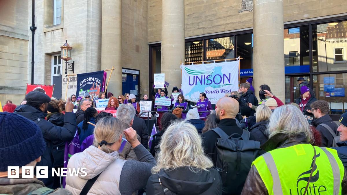 A group of protesters holding Unison signs stand outside Shire Hall in Gloucester