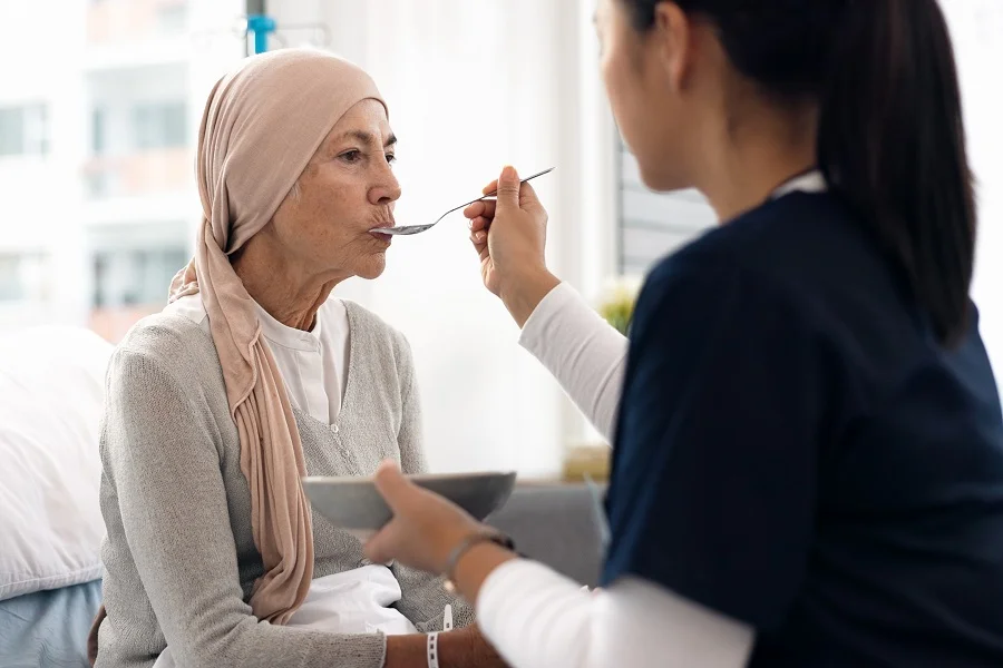 Nurse feeding cancer patient