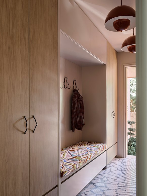 Teamed with warm timbers and black detailing, soft pink cabinetry and floor tiles in this Sydney home designed by Greg Natale created an inviting entry.