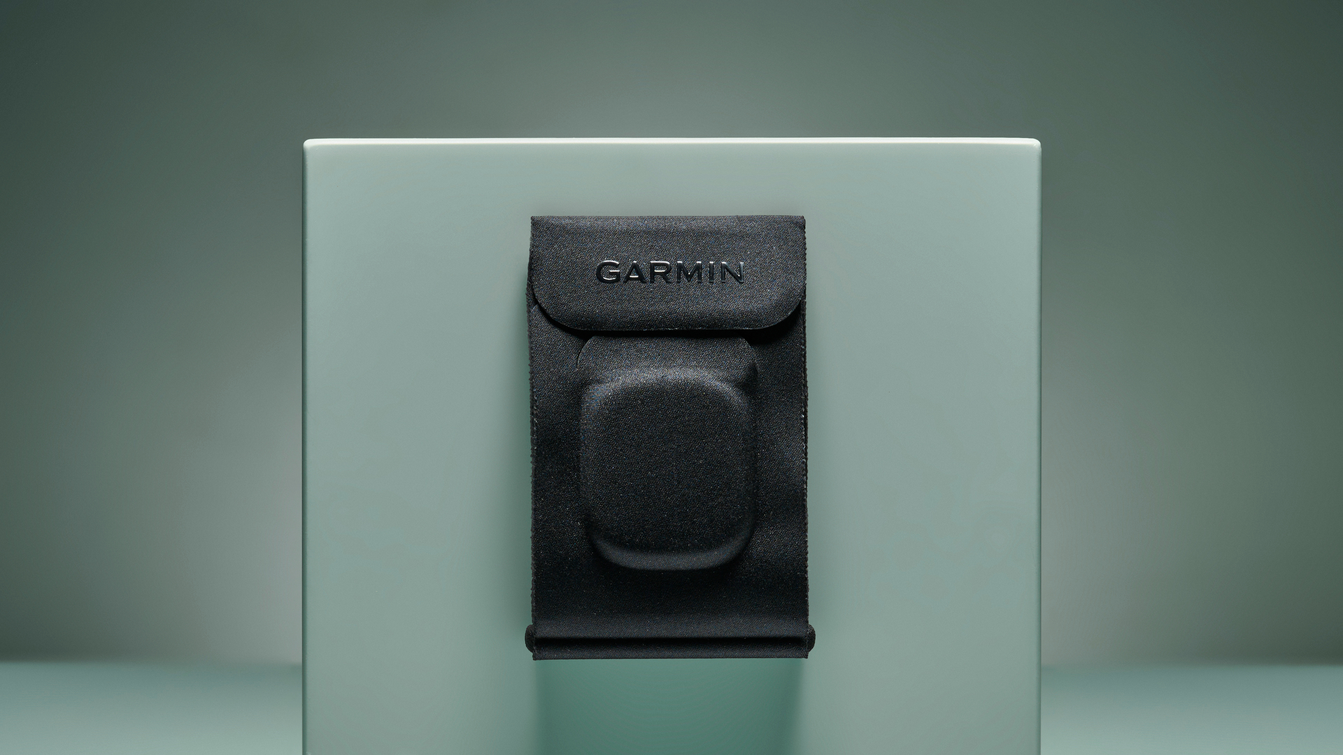 Black fabric Garmin Index Sleep Monitor armband pinned on turquoise box