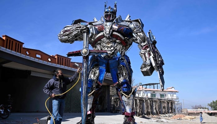 This photograph, taken on February 12, 2026, shows sculptor Ehtisham Jadoon working on a model of Optimus Prime, a film character from Transformers, made from scrap metal at his studio on the outskirts of Islamabad. — AFP