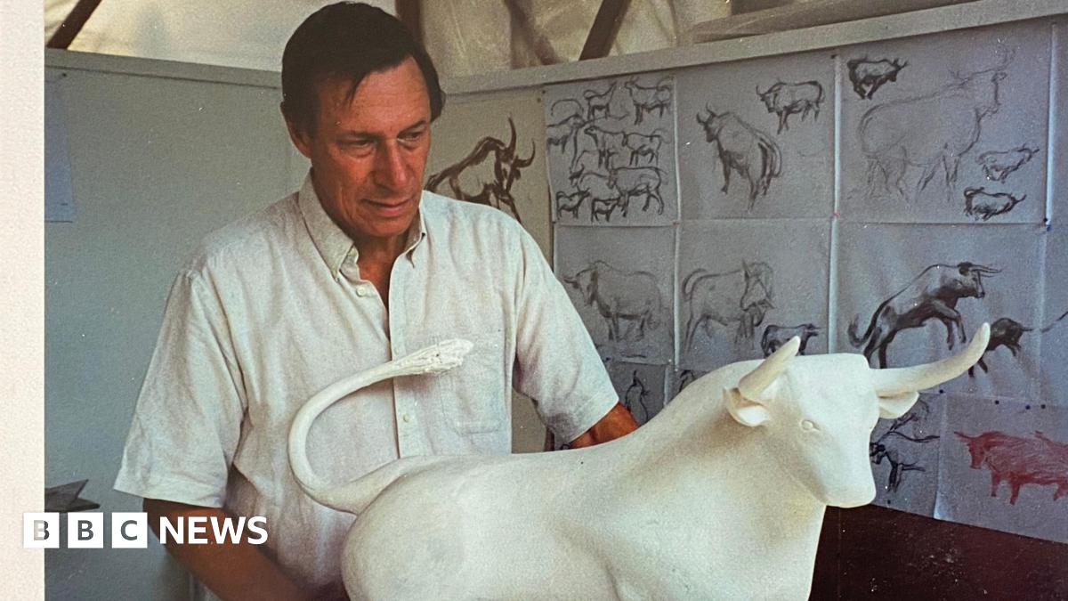 Sculptor Laurence Broderick standing behind the maquette the Bull with previous sketches behind him