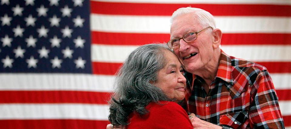 A couple hold each other in front of the American flag.