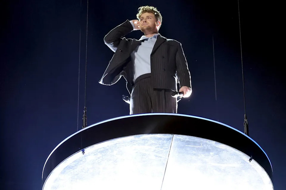 Alex Warren fumbling with his ear piece. Kevin Winter/Getty