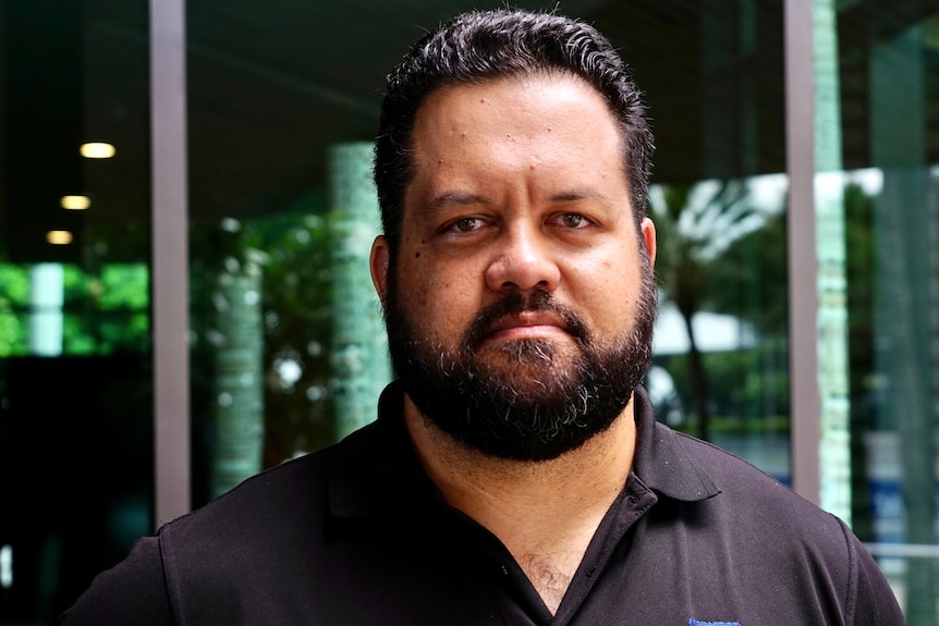 A man with a beard and wearing a black polo shirt