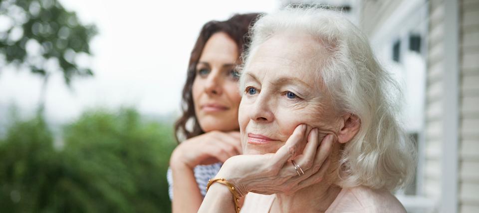 An older woman and a younger woman looking over a balcony.