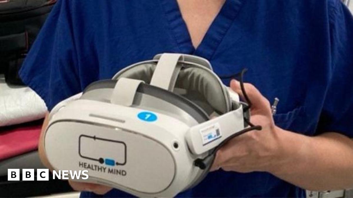 A woman in nursing scrubs holding a virtual reality headset