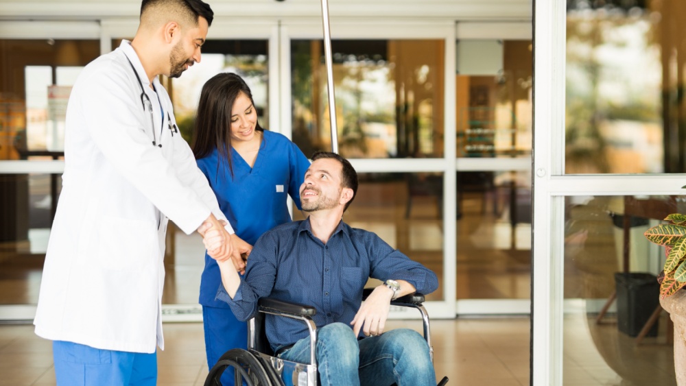 A person being discharged from  hospital ba a doctor and a nurse.