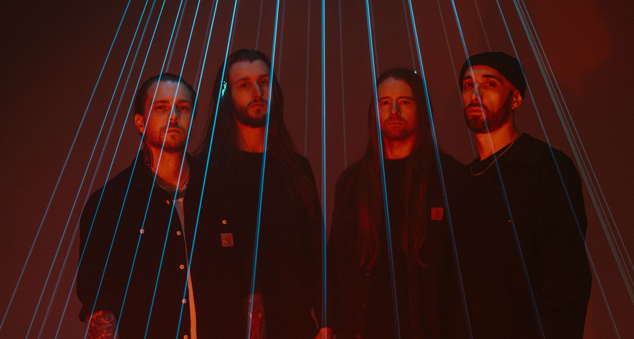A portrait of UK metal stalwarts Sylosis, pictured under an array of laser beams [L-R] Bassist Ben Thomas; guitarist Conor Marshall; frontman/guitarist Josh Middleton; drummer Ali Richardson.