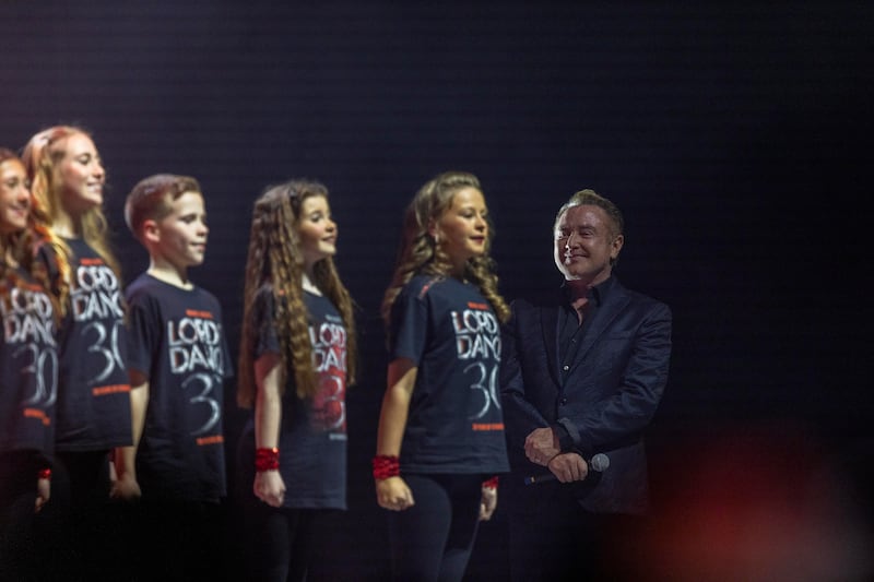 Michael Flatley on stage with cast members.
