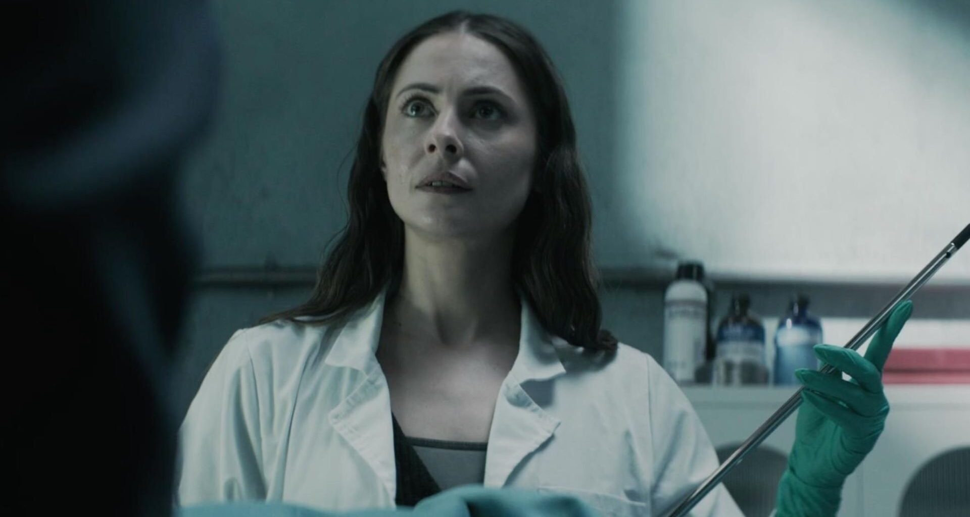Willa Holland as Rebecca Owens in The Mortuary Assistant, holding a long needle