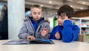 Two young children reading a book in a library.