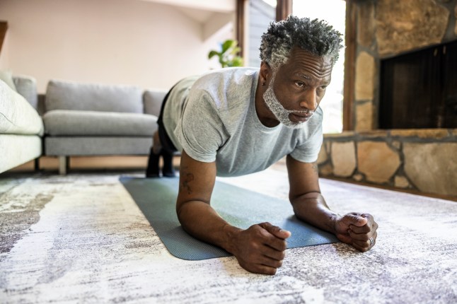 Senior man practicing yoga in living room