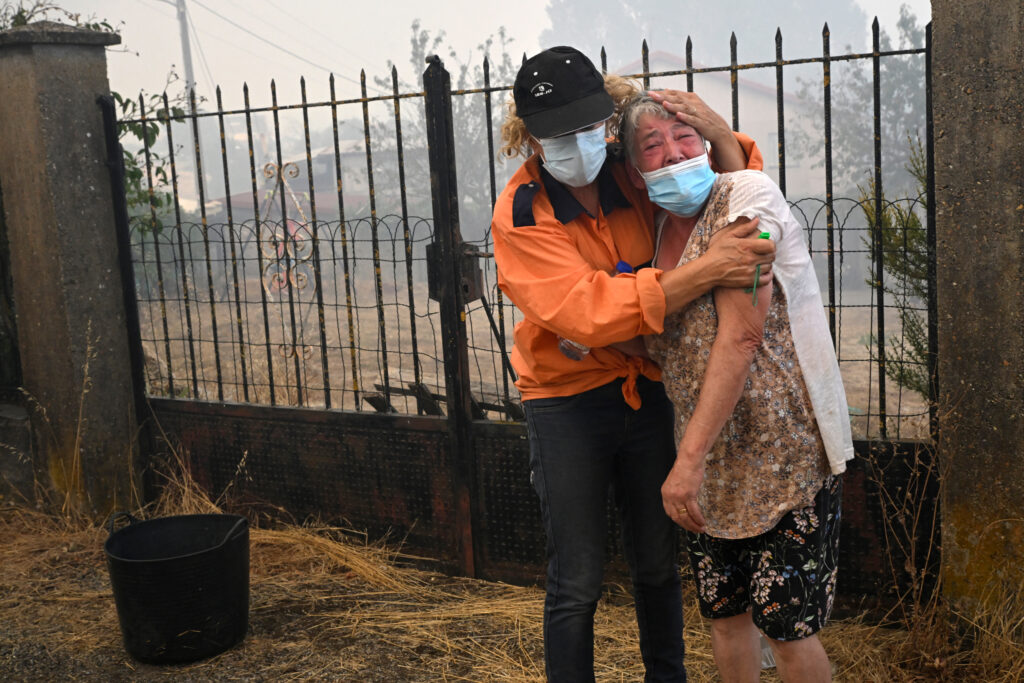 A Civil Protection member comforts a woman as a wildfire burns in the village of Veiga das Meas, Spain, on Aug. 16, 2025. Increasingly severe wildfire seasons around the world are one of the signs that some forests are at a climate threshold. Credit: Miguel Riopa/AFP via Getty Images