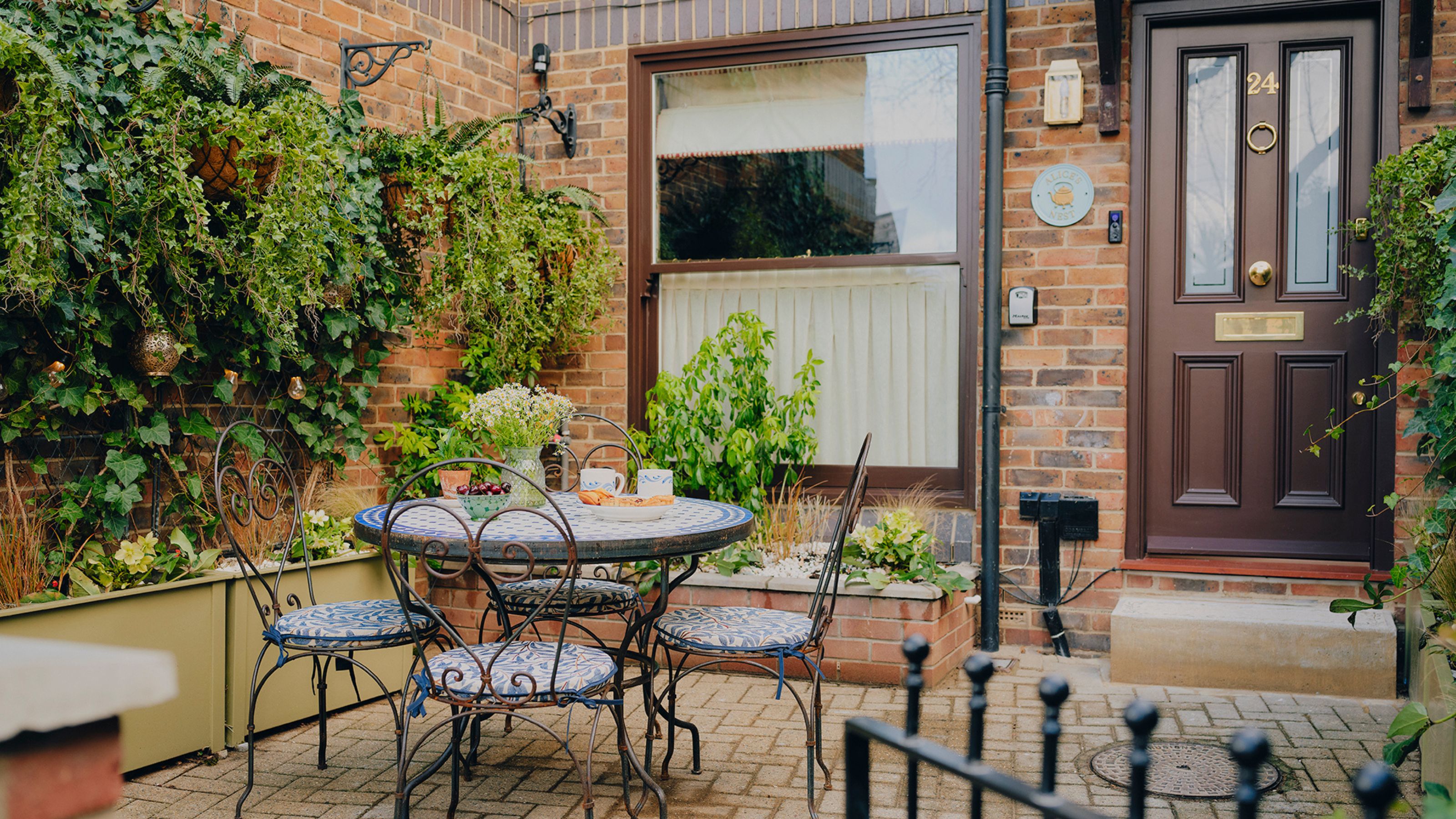 a Canada Water 1980s brick apartment with dark brown front door and windows with a small courtyard garden