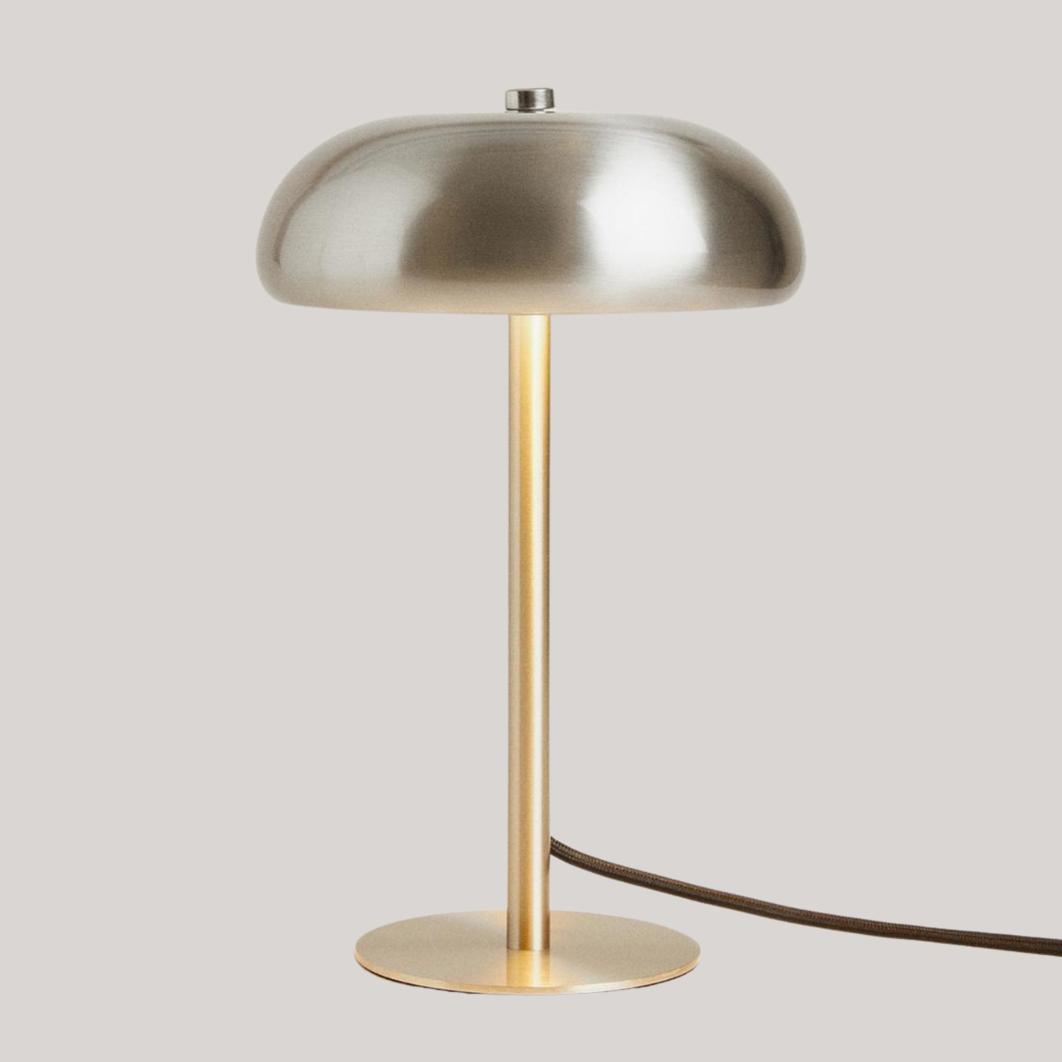 Small Monochrome Table Lamp with warm light sits against pale grey background.