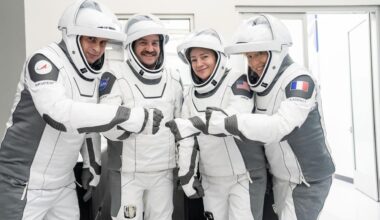 four people in white flight suits pose for a picture