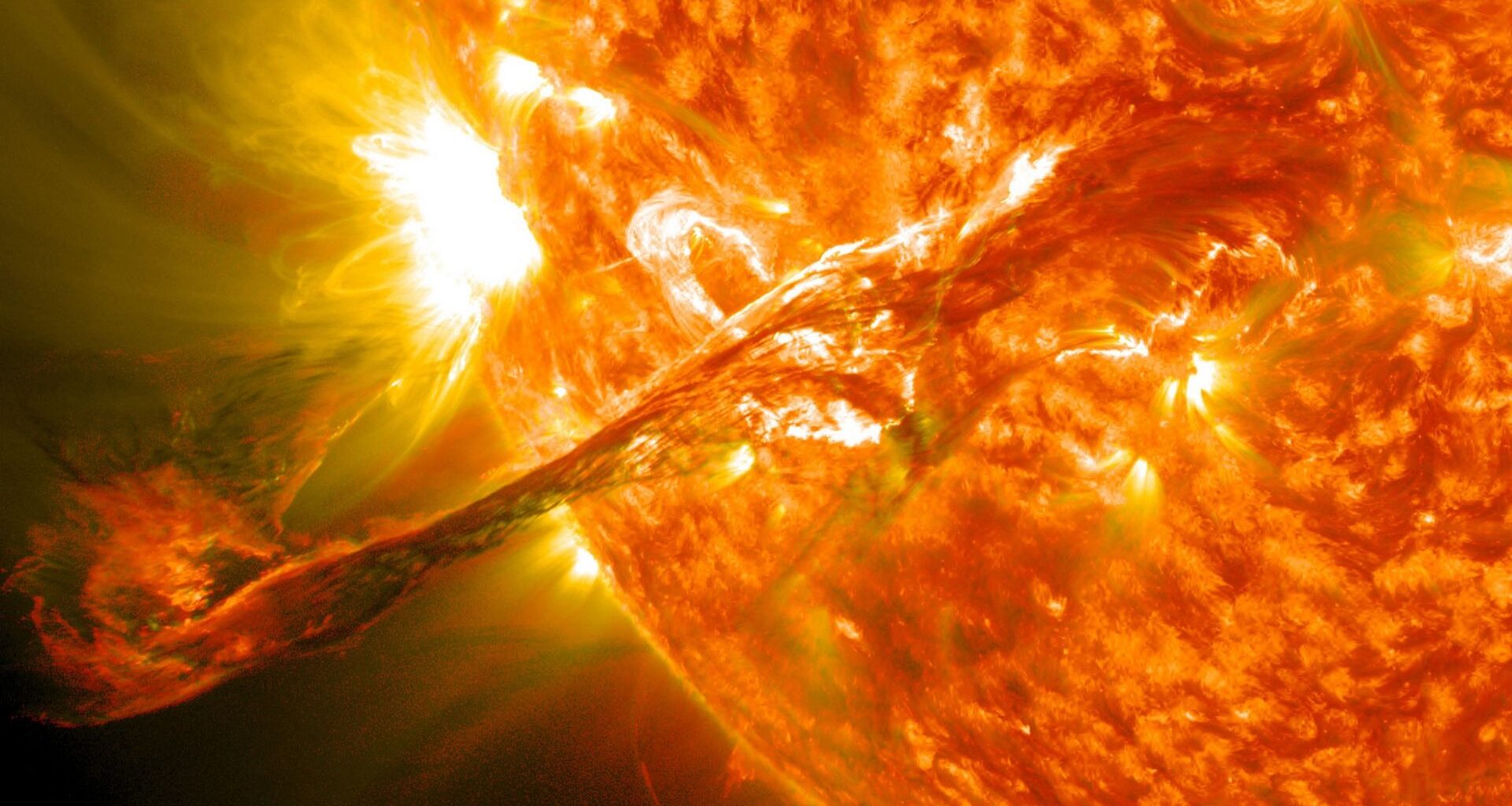An illustration of a close up on our sun, with the golden ball of orange gas ejecting material to the bottom left of the image.