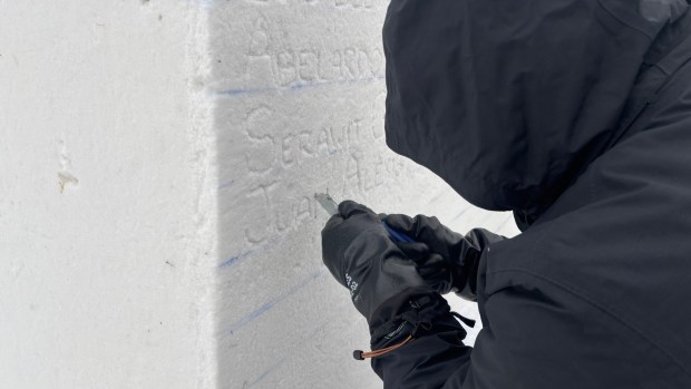Snow sculptor Logan Thomas carves names into a snow block on Feb 1, 2026, near Lake of the Isles in Minneapolis. The names are of people who have died in federal immigration custody or been killed by agents as immigration enforcement efforts have ramped up in 2025 and 2026. (Jared Kaufman / Pioneer Press)