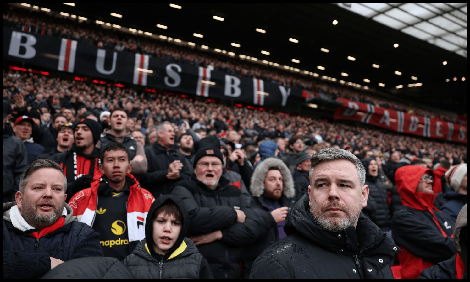 Manchester United fans pay tribute to the victims of the Munich Air Disaster with a Busby Babes flag.