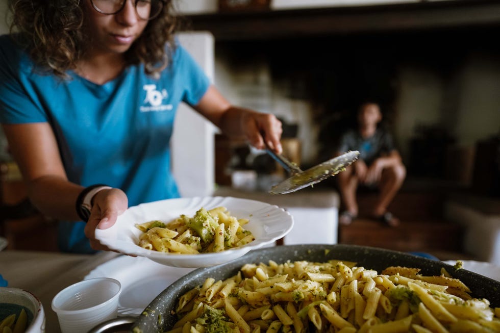 Serving pasta from a large dish to a plate.