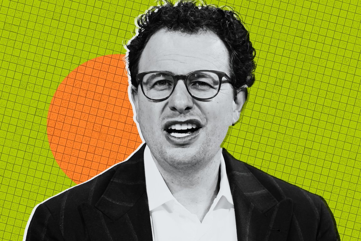 Anthropic CEO Dario Amodei is shown with curly dark hair and glasses is wearing a dark pinstripe suit jacket over a white shirt. He has a slightly open mouth expression. The background is a green grid pattern with an orange circle behind his head.