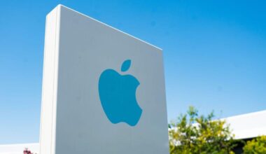 A bright blue Apple logo appears on a sign in front of its California headquarters