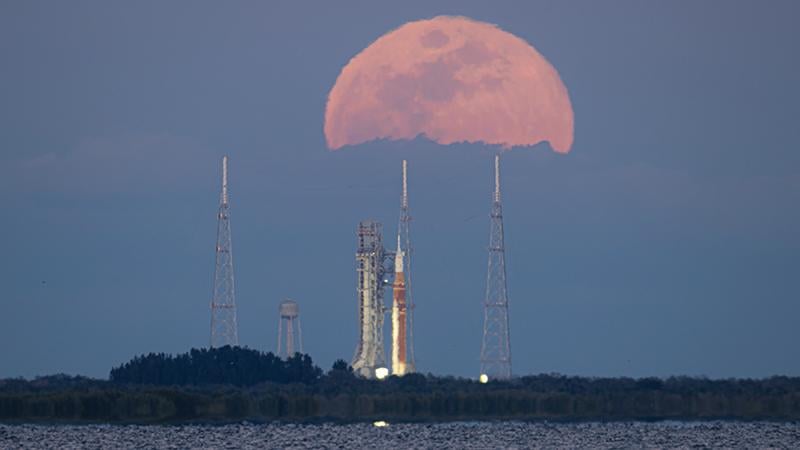 Space Launch System rocket and Orion spacecraft on launcher against rising Moon