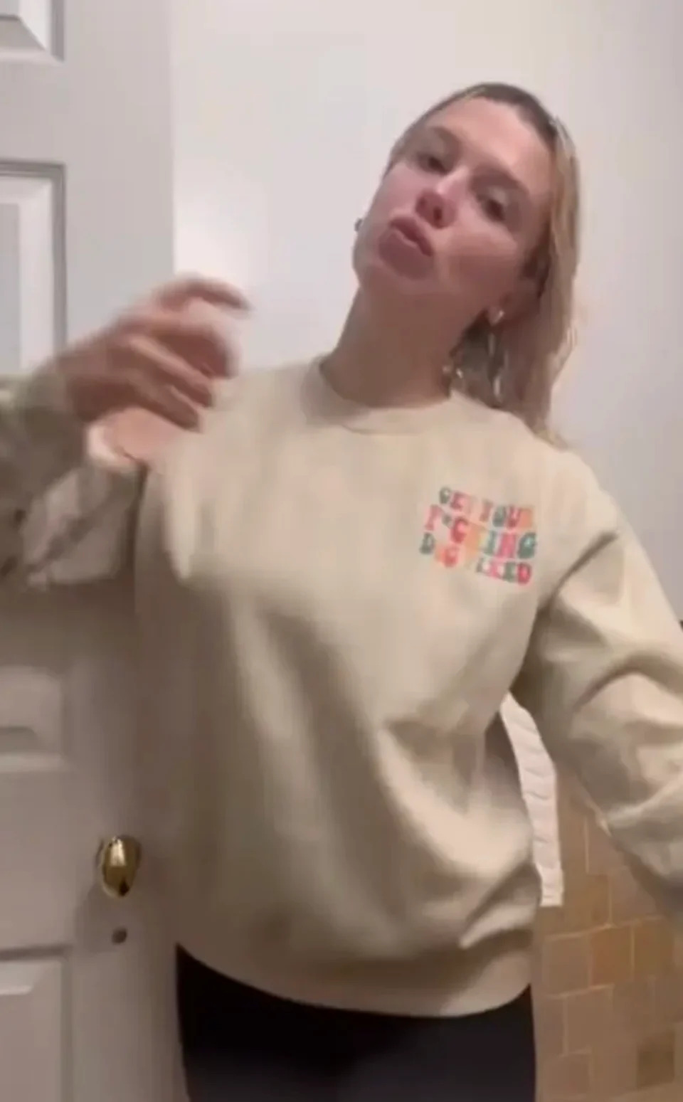 Millie spraying herself with perfume in a bathroom