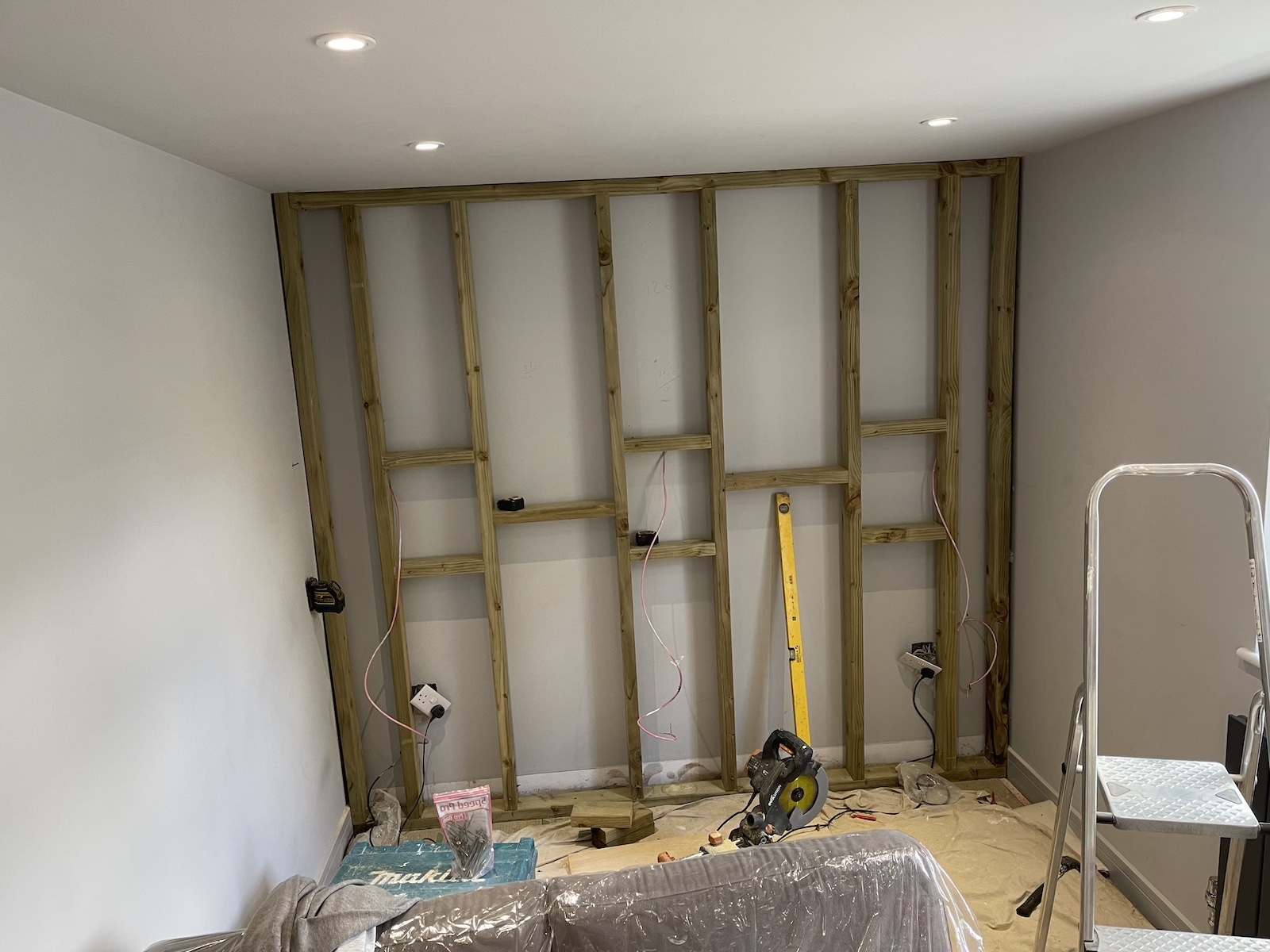 An image of a stud wall being constructed for three in-wall speakers to be embedded