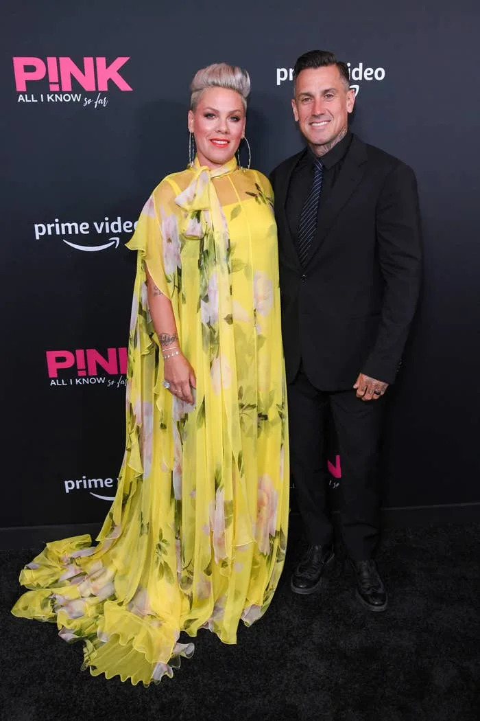 Pink in a flowing floral dress and Carey Hart in a suit on the red carpet