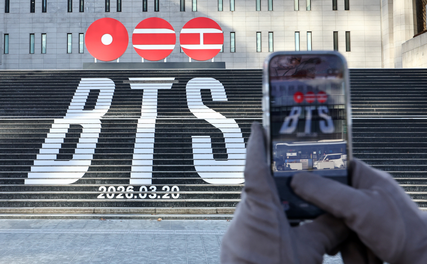 A pedestrian takes a photo of a promotional sign for BTS's fifth full-length album set to release in March, at Jongno District, central Seoul, on Jan. 22. [NEWS1]