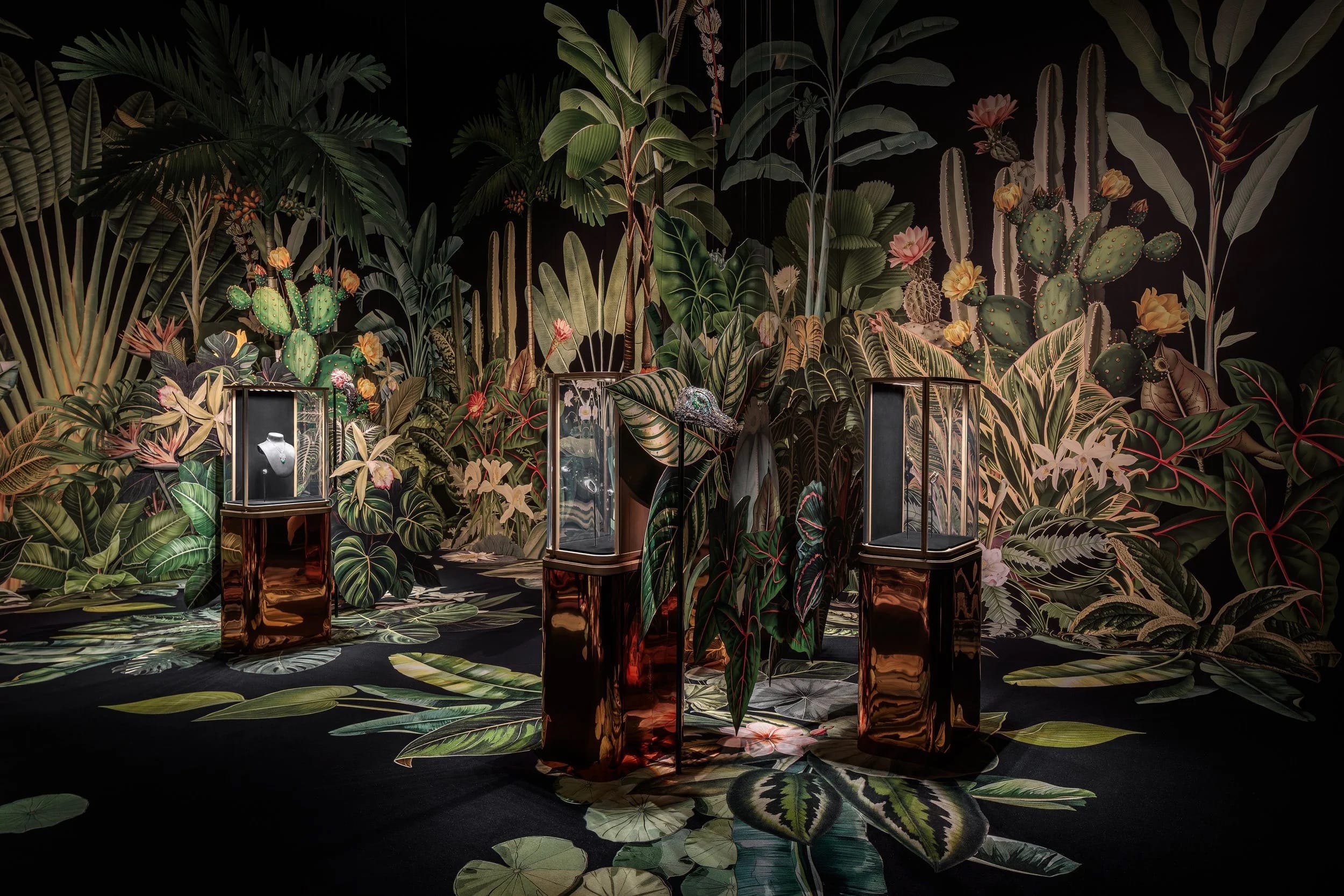 A colorful retail installation for Cartier by Clare Celeste of foliage against a black background, interspersed with cases of jewelry