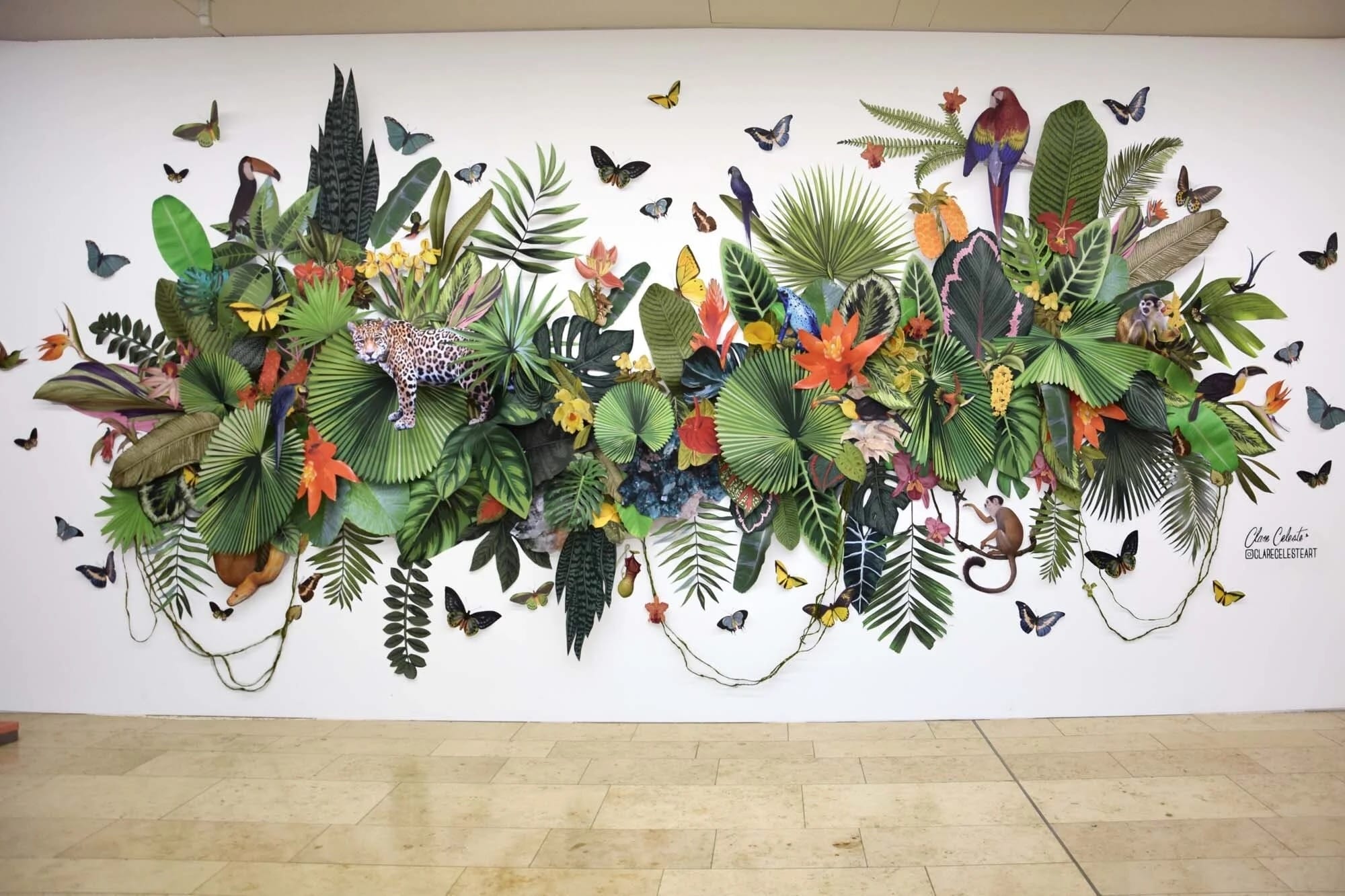 A paper installation by Clare Celeste of jungle foliage and animals on a wall
